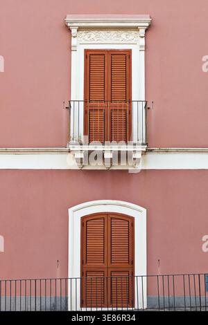 Terracotta facade with wooden shutters and balcony on historic Mediterranean building Stock Photo