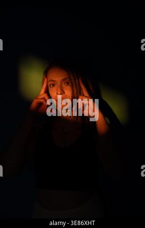 Woman with dreadlocks illuminated by dramatic lighting, creating artistic shadow play Stock Photo