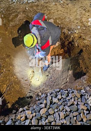 Worker digs the hole in the ground with a shovel, top view Stock Photo