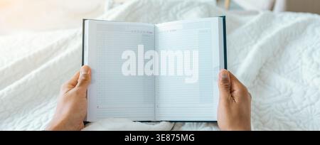 Holding a Blank Notebook in Bed While Getting Ready for the Day Ahead Stock Photo