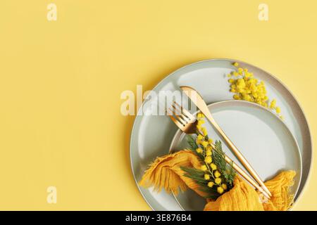Festive Spring Table Decor with Mimosa Flowers and Cutlery Stock Photo