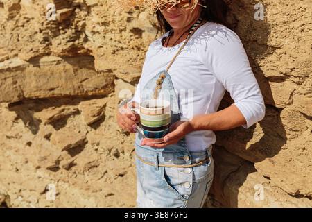Close up of womans hands holding coffee mug at the beach Stock Photo