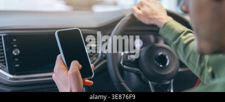 Man Using Smartphone While Driving in Modern Car Interior During Day Time Stock Photo