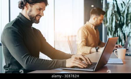 Two Men Working on Laptops in an Office During the Evening Stock Photo