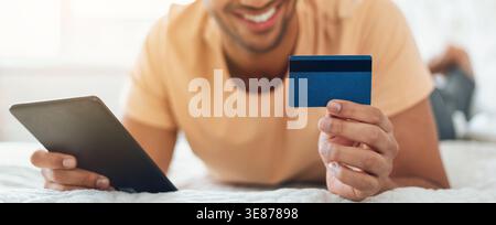 Man Uses Tablet and Holds Credit Card While Shopping Online From Home on a Weekend Stock Photo