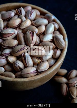 Pistachios in wooden bowl on dark background Stock Photo