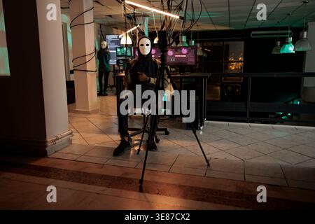 Ransomware, cyber criminal recording threat video on smartphone, asking money for ransom, calling victim. Phishing, blackmail, man scammer in mask stealing information at night time Stock Photo