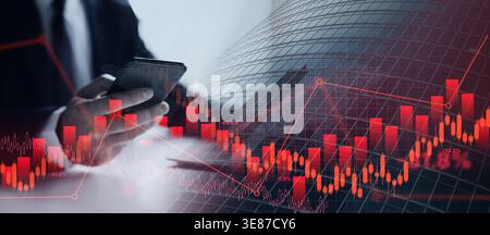 Man Using Smartphone While Analyzing Stock Market Data During Work Hours in Office Setting Stock Photo
