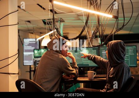 Cybercrime, hackers planning ransomware attack, hacking server, stealing data, discussing illegal malware code. Scammers cracking computer system password at night time, information leak Stock Photo