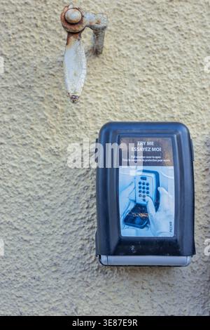 Pont, Cote-d'Or, France - April 12, 2026: A secure key box for vacation rentals mounted on a wall next to a traditional French window shutter holder. Stock Photo