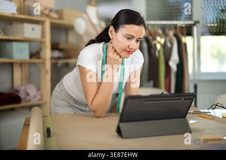 Woman dressmaker makes pattern using drawing on tablet Stock Photo