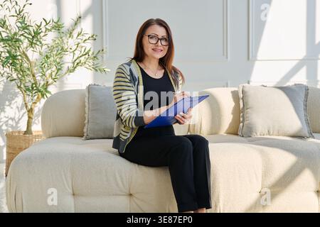 Portrait of professional psychologist therapist woman taking notes on clipboard in office Stock Photo