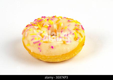 A single, glossy doughnut with pink and yellow sprinkles on a light-colored surface, against a softly focused background Natural lighting with diffuse Stock Photo