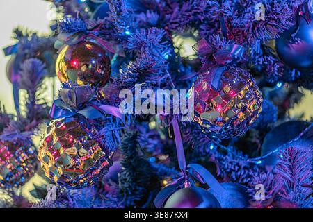 Close-up of a decorated Christmas tree in a casino interior, predominantly gold, purple, blue, and red ornaments with iridescent quality, warm indoor Stock Photo