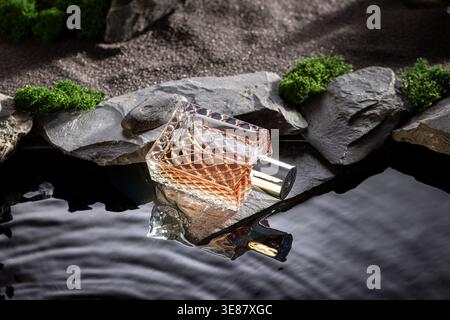 Untamed golden perfume illuminated by moonlight on black water. Perfume at water in moon landscape. Stock Photo