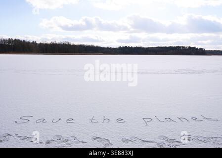 Written SAVE THE PLANET on snow background message ice outdoor on ground in winter. Writing text sign drawing on field in frozen background. Weather changing cold season has arrived environment protection crisis heatwaves climate anxiety. Mockup Copy space for text Creative art and texture  Stock Photo