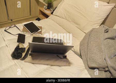 Digital devices creating a study and work area on a comfortable bed Stock Photo