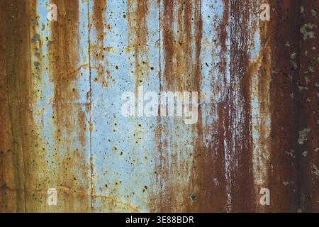 Close-up of long brownish rust streaks, stains and small holes on old light bluish painted concrete wall surface in poor and damaged condition, Quebec Stock Photo