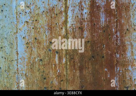 Close-up of long brownish rust streaks, stains and small holes on old light bluish grey painted concrete wall surface in poor and damaged condition, Q Stock Photo