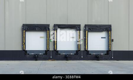 Three empty loading docks with closed doors ready for logistics and cargo dispatch Stock Photo