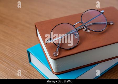 A round eyeglasses on a stack of hardcover books. Reading, education, intellect concept. Copy space for text. Stock Photo
