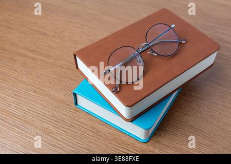 A round eyeglasses on a stack of hardcover books. Reading, education, intellect concept. Copy space for text. Stock Photo