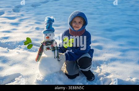 Child Hug Snowman Child Play With Snowman In Snow Field Kids Winter child-hug-snowman-child-play-with-snowman-in-snow-field-kids-winter