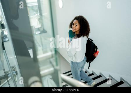 College student moving through building with study materials and backpack. Stock Photo