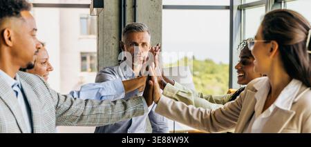 Energetic diverse group celebrates success with teamwork and joy Stock Photo