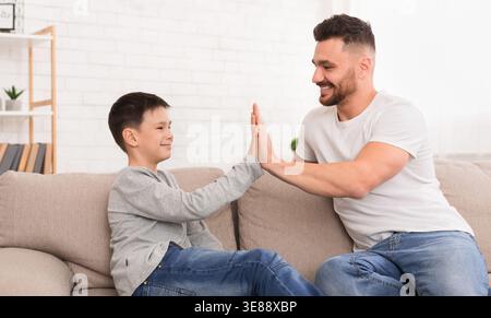 Father and son giving high five to each other at home Stock Photo