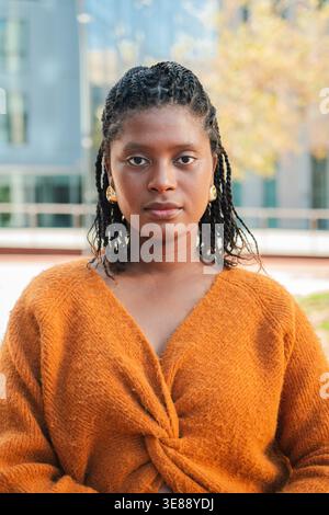 Confident young woman with braided hair showcasing a serene expression while engaging in outdoor activities that highlight her poise and grace in a Stock Photo
