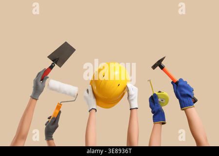Hands with hardhat and construction tools on beige background Stock Photo