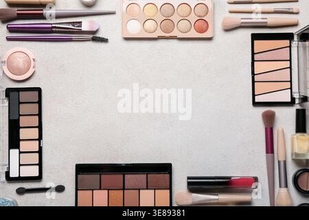Frame made of makeup brushes and cosmetic products on beige grunge background, closeup Stock Photo