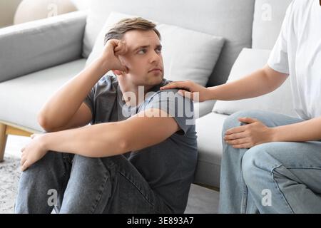 Young woman supporting man with suicidal thoughts at home Stock Photo