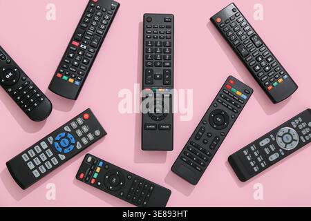 Different modern TV remote controls on pink background Stock Photo