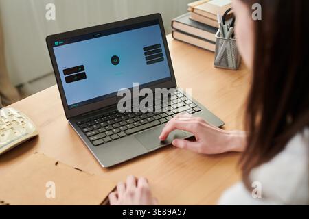 Young adult woman using laptop with VPN dashboard, managing online privacy and secure connection for remote work. Useful for cybersecurity, data protection, internet safety marketing Stock Photo
