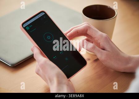 Close up of young adult woman holding smartphone, activating VPN security app for private browsing and data protection. Ideal for cybersecurity, mobile privacy, remote work marketing Stock Photo