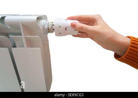 Woman adjusts temperature on white radiator thermostat. Hand turns valve control knob for heating system. Home climate regulation and energy efficienc Stock Photo