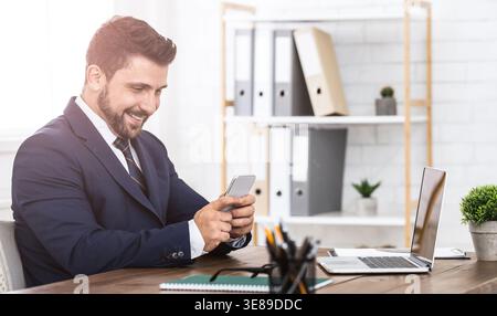 Chatting with pleasure. Businessman using phone at workplace Stock Photo
