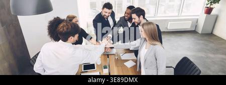 Young team joining hands involved in teambuilding activity Stock Photo