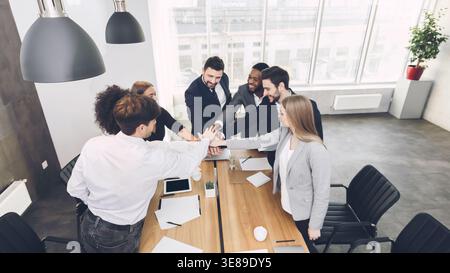 Excited colleagues joining hands involved in teambuilding activity Stock Photo