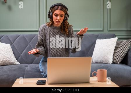 Woman having a conversation on her laptop. She is having video call, feeling anxious and distraught. Stock Photo