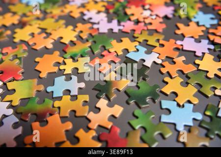 A high-angle view of various multicolored jigsaw puzzle pieces scattered on a dark surface. The image represents concepts of complexity, strategic thi Stock Photo