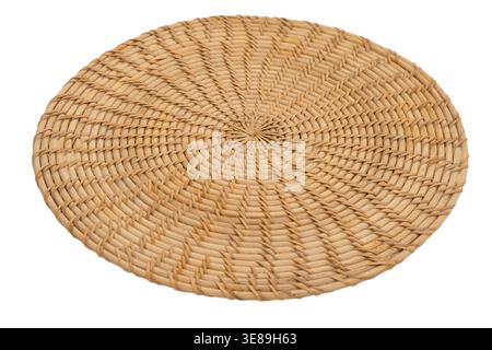 Round woven mat made of natural rattan. Decorative braided placemat for kitchen table setting. Eco friendly kitchenware item isolated on white backgro Stock Photo