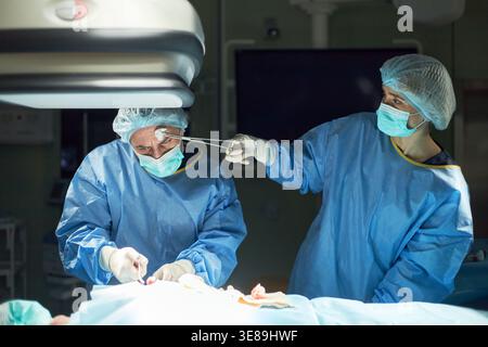 Surgeons performing operation in operating room, collaborating with surgical instruments over patient. Ideal for healthcare marketing, hospital services, surgery concepts Stock Photo