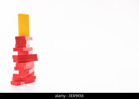 Yellow wooden block standing on stack of red ones Stock Photo