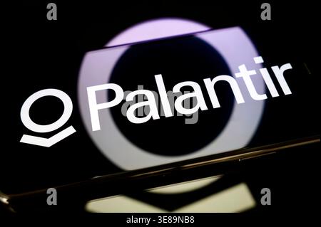 Paris, France - April 10, 2026: The Palantir logo on a smartphone screen, placed on a reflective surface with a glowing circular light projection. Stock Photo
