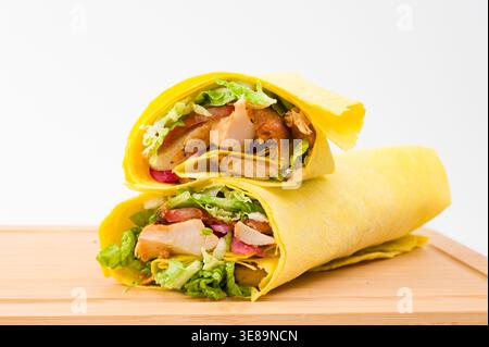 Two vibrant chicken wraps filled with crisp lettuce and colorful vegetables, resting on a smooth wooden board, perfect for a healthy lunch or snack. Stock Photo