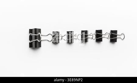 Collection of Black Binder Clips Arranged in a Straight Line on a White Surface for Display Stock Photo