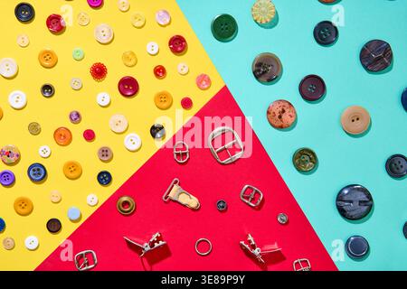 Creative flat lay composition of colorful sewing accessories including buttons and metal buckles arranged on a vibrant geometric background. Mockup, f Stock Photo